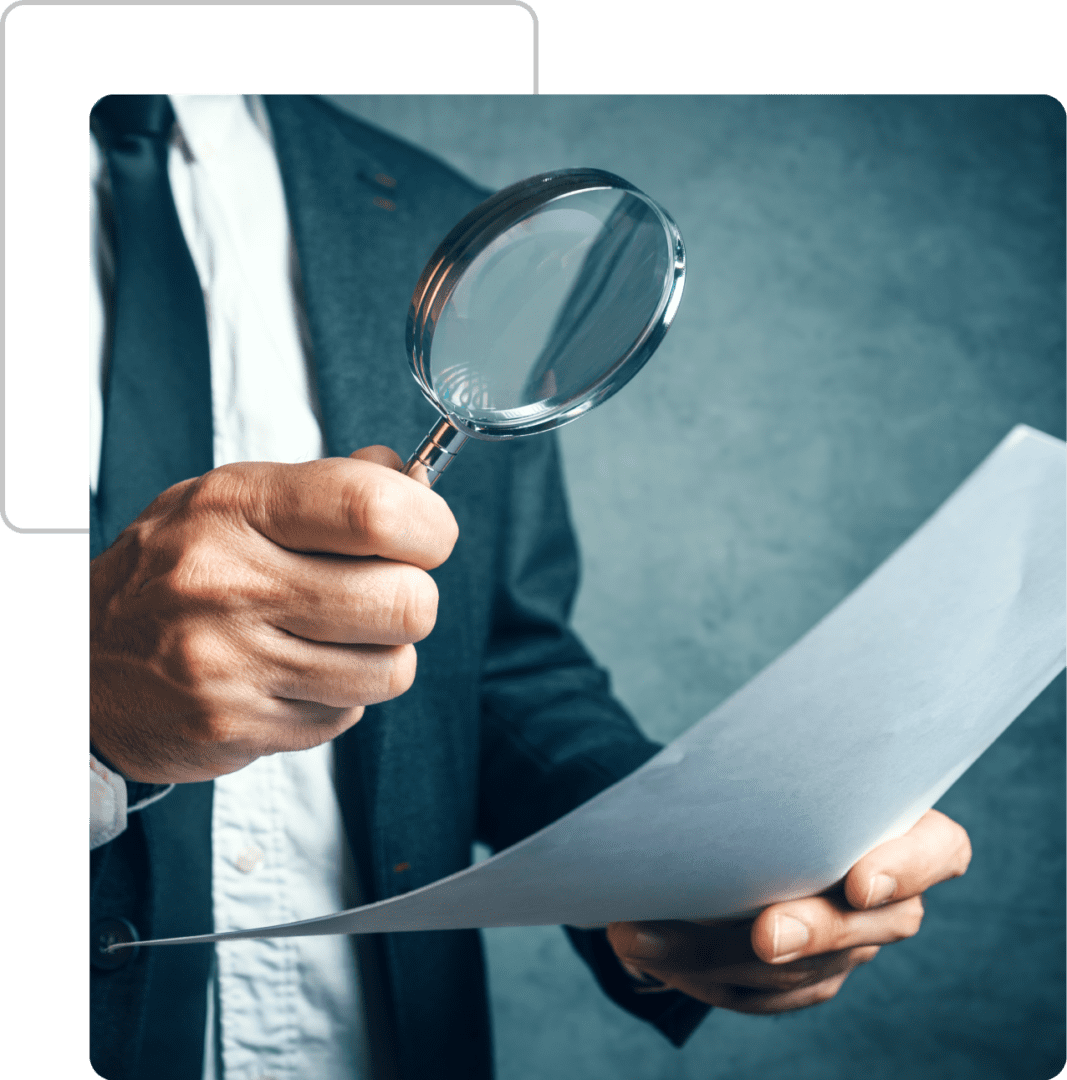 A person holding a magnifying glass over papers.
