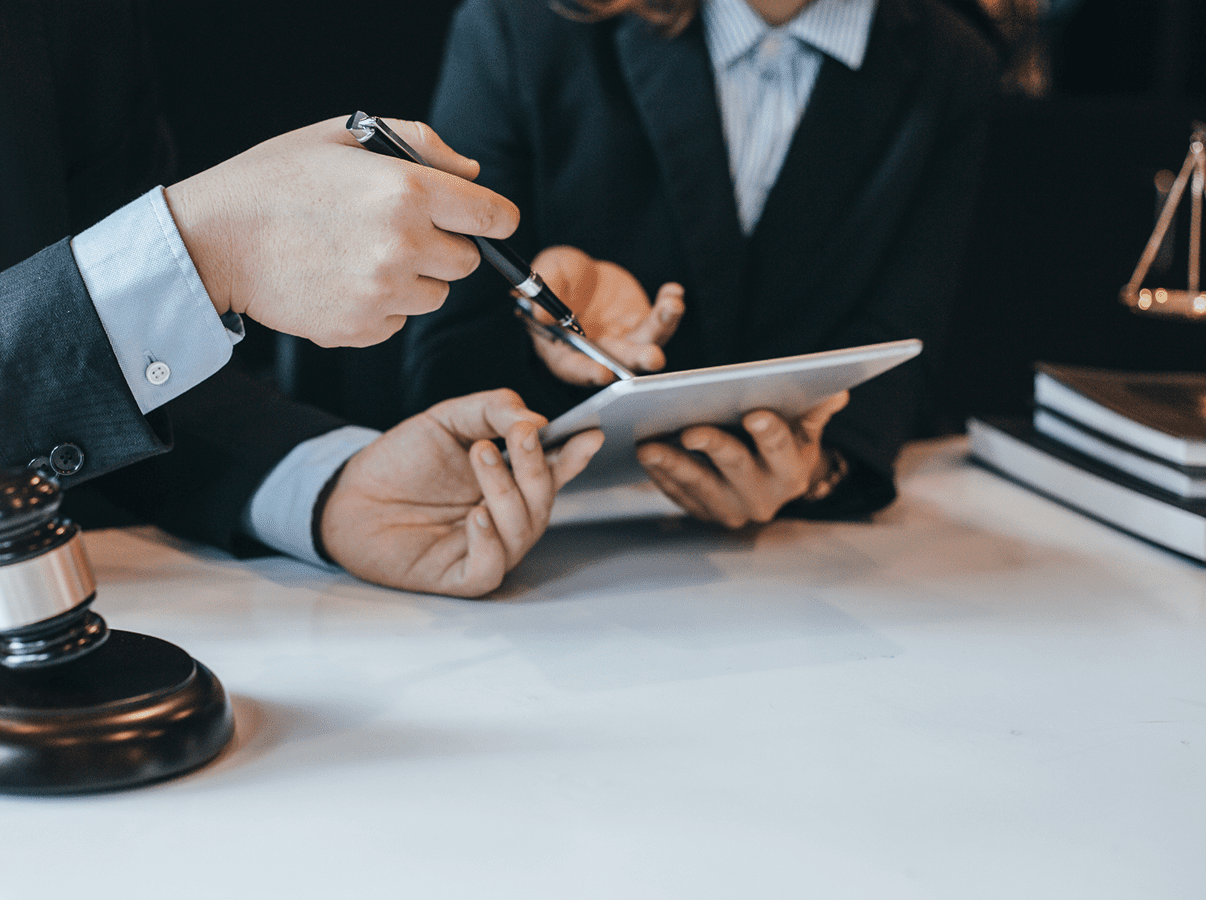 Two people sitting at a table with papers and pens.